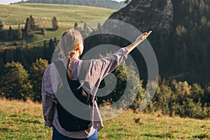 Woman hiker with backpack open arm at mountain peak. Travel and active lifestyle concept. 30s girl enjoying valley view