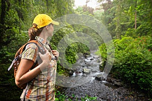 Woman hiker with backpack standing and enjoying rain forest and