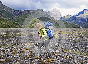 Woman hiker with backpack walking up the trail with beautiful mountain peaks view landscape