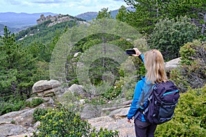 Woman hiker from behind taking picture of landscape with mobile phone. Female trekker photographing in nature