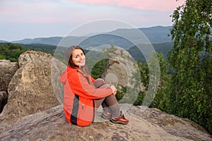 Woman hiker on big rock on top of the mountain