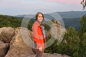 Woman hiker on big rock on top of the mountain