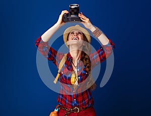 Woman hiker on blue background with DSLR camera taking photo