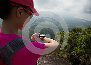 Woman hiker checking the altimeter on seaside mountain peak