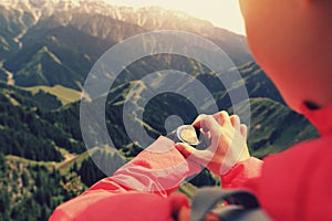 Woman hiker checking the altimeter on sports watch at mountain peak