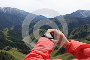 Woman hiker checking the altimeter on sports watch at mountain peak