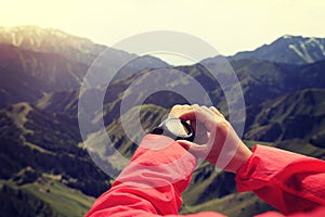 Woman hiker checking the altimeter on sports watch at mountain peak