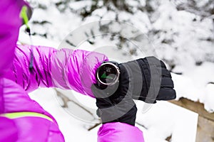 Woman hiker checking sports watch in winter woods and mountains