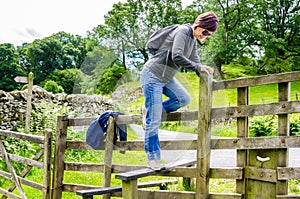 Woman Hiker Climbing over a Fence on a Sunny Spring Day