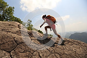 woman hiker climbing rock on mountain peak cliff