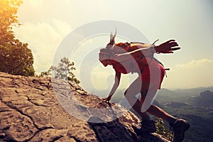 Woman hiker climbing rock on mountain peak cliff