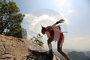 Woman hiker climbing rock on mountain peak cliff