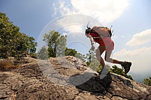 Woman hiker climbing rock on mountain peak cliff