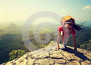 woman hiker climbing rock on mountain peak cliff