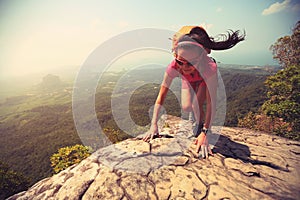 woman hiker climbing rock on mountain peak cliff