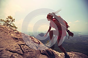 woman hiker climbing rock on mountain peak cliff