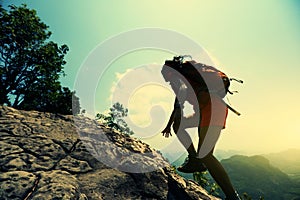 Woman hiker climbing rock on mountain peak cliff