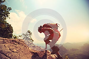 Woman hiker climbing rock on mountain peak cliff