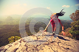 Woman hiker climbing rock on mountain peak cliff