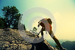 Woman hiker climbing rock on mountain peak cliff