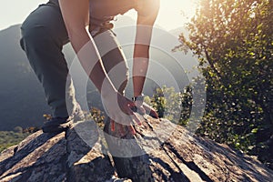 woman hiker climbing rock on mountain top