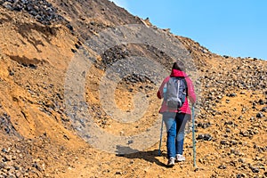 Hiker using hiking poles going up a steep rocky mountain path in Iceland