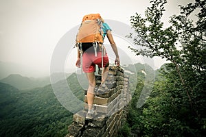 Woman hiker climbing up on the top of great wall