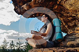 Woman hiker enjoy the view at sunset mountain peak cliff sitting in relax pose