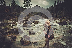 Woman hiker enjoying amazing landscapes near wild mountain river.