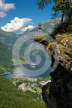 Woman hiker enjoying scenic landscapes at a cliff edge, Geirangerfjord