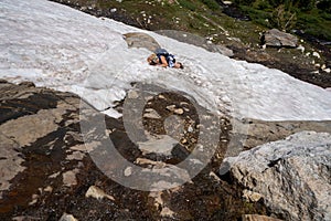 Woman hiker gets stuck on a cliff in a snowfield. Concept for dangerous hiking, hiking solo photo