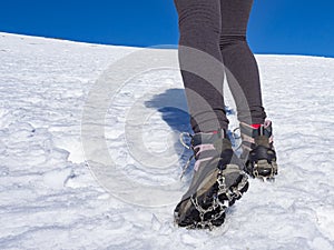 Woman hiker on a glacier with crampons on boots