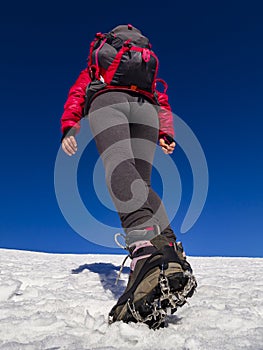 Woman hiker on a glacier with crampons on boots