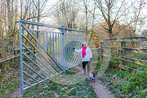 Woman hiker with her dachshund standing by metal revolving door at entrance to nature reserve