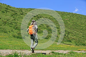 Woman hiker hiking in grassland mountain trail