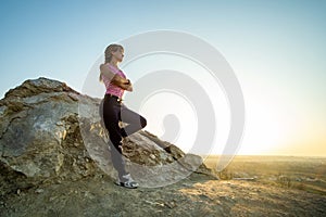 Woman hiker leaning on a big rock enjoying warm summer day. Young female climber resting during sports activity in nature. Active