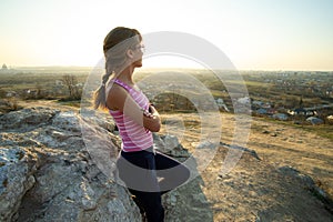 Woman hiker leaning on a big rock enjoying warm summer day. Young female climber resting during sports activity in nature. Active