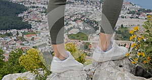 Woman hiker legs stand on mountain peak rock