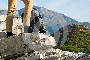 Woman hiker legs stands on the edge of the mountain cliff against beautiful mountains peak