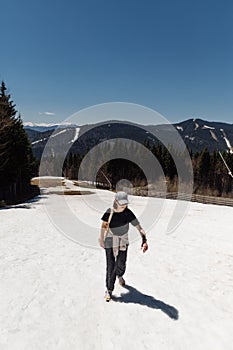 Woman hiker in light casual clothes climbs the mountains in the snow while walking in a mountain resort. Vertical