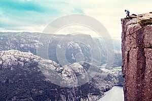 Woman hiker looking down stands on the famous Preikestolen Pulpit Rock