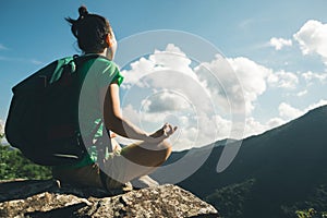 woman hiker meditation on mountain top cliff edge