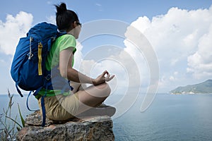 woman hiker meditation on mountain top cliff edge