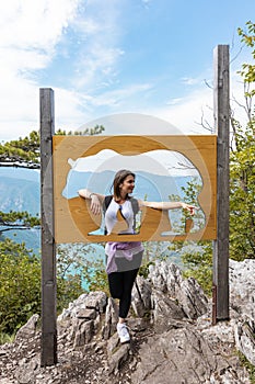 Woman hiker at mountain forest posing beside bear sign at natural reserve