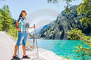 Woman hiker in the mountains looks at the telescope