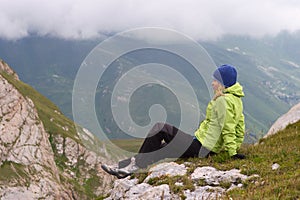 Woman Hiker in Mountains relaxing sitting on rocky cliff