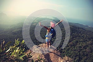 Woman hiker open arms hiking on mountain peak