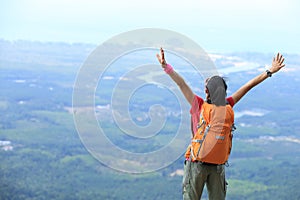 Woman hiker open arms at mountain peak