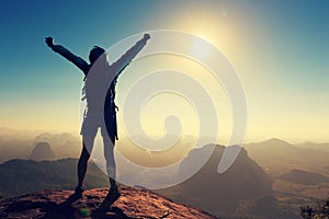 Woman hiker open arms on sunrise mountain top photo