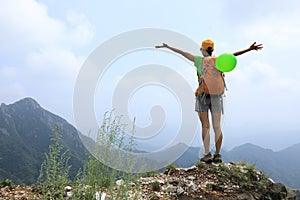 Woman hiker open arms on the top of mountain